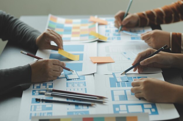 Close up ux développeur et ui concepteur brainstorming sur l'interface d'application mobile wireframe conception sur la table avec le client breif et le code couleur au bureau moderne agence de développement numérique créatif