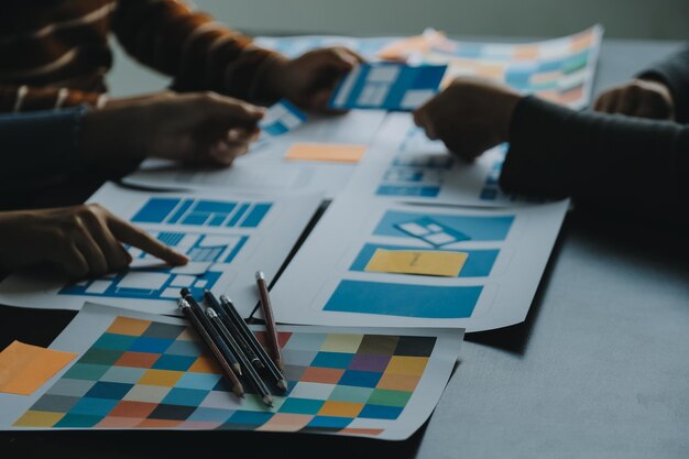 Close up ux développeur et UI designer brainstorming sur l'interface d'application mobile wireframe design sur la table avec le client breif et le code couleur au bureau moderne agence de développement numérique créatif