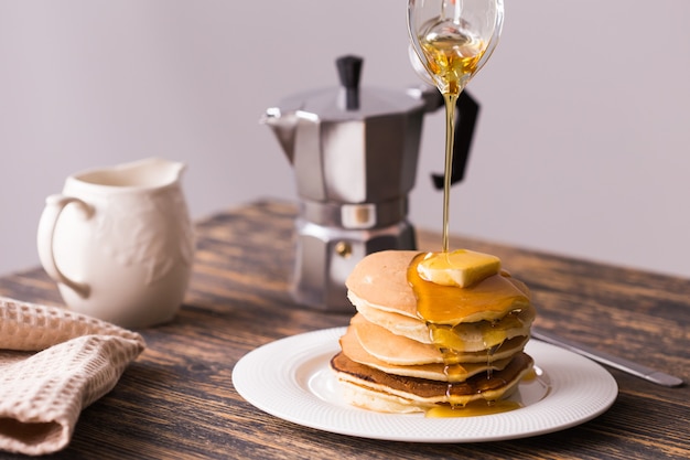 Close-up de verser le sirop d'érable sur pile de crêpes