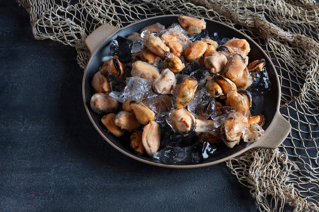 Close-up de viande de moules pelées congelées sur de la glace pilée