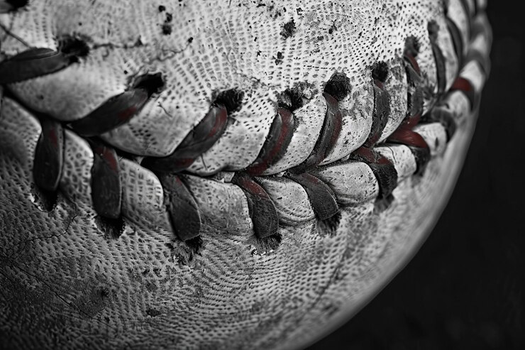 Photo close-up d'une vieille balle de baseball avec des coutures et une texture visibles sur un fond noir avec de l'espace pour