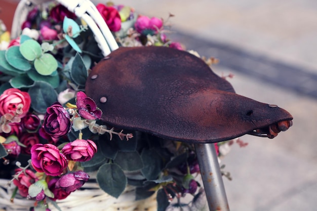 Close-up d'un vieux siège de vélo par des roses