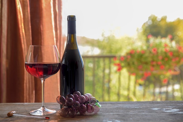 Close-up de vin rouge avec bouteille et raisins artificiels sur la table à la maison