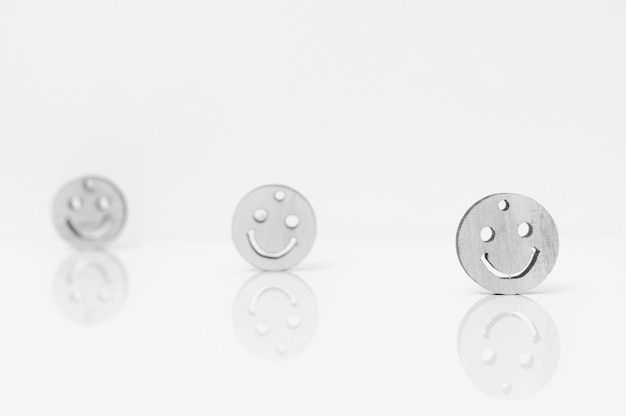 Close-up de visages souriants métalliques avec réflexion sur fond blanc