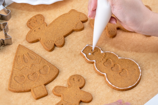 Close up woman décore des biscuits de pain d'épice de Noël