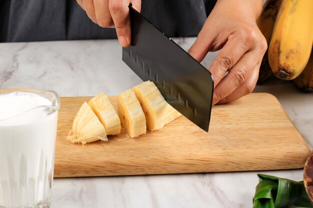 Close Up Woman Hand Slicing Banana, préparation faisant une compote de patates douces à la banane (Kolak Pisang Ubi). Kolak est populaire pour le petit-déjeuner du Ramadan