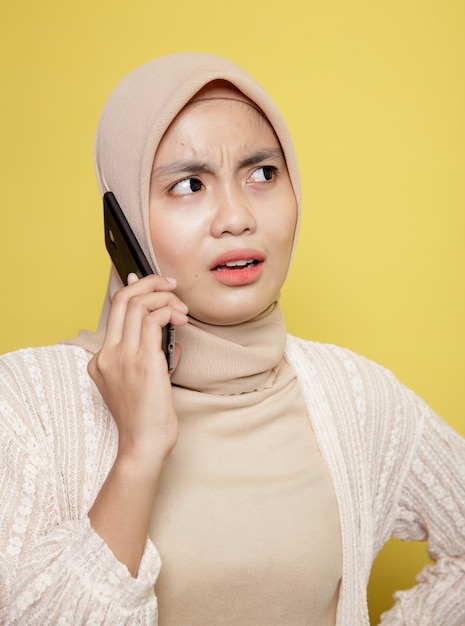 Close up woman hijab avec une expression de téléphone appelant isolé sur fond jaune