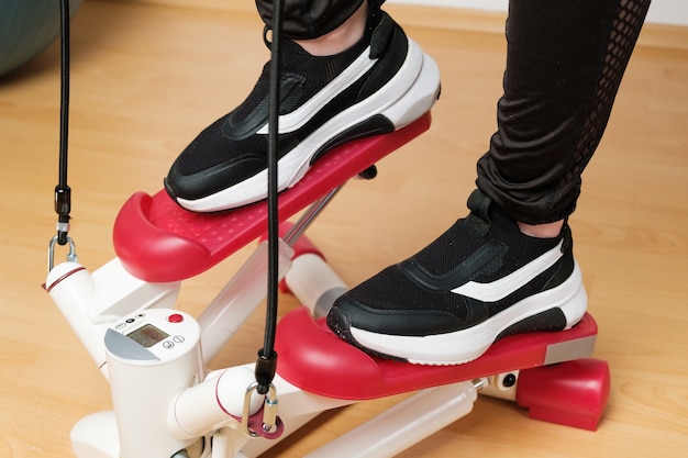 Close up womans pieds dans les baskets de formation sur le stepper twist