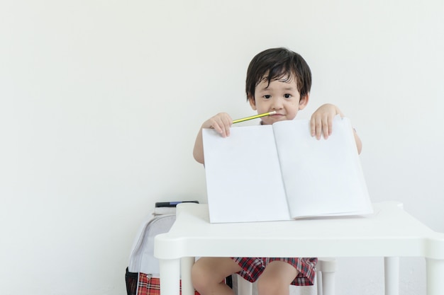 Closeup asain kid montrer un cahier après l&#39;école sur le mur de ciment blanc