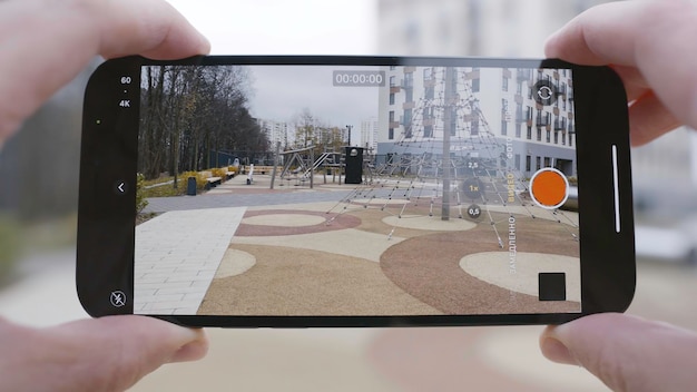 Photo closeup de l'écran du téléphone prenant l'action vidéo homme tient le téléphone et prend la vidéo de l'aire de jeux et