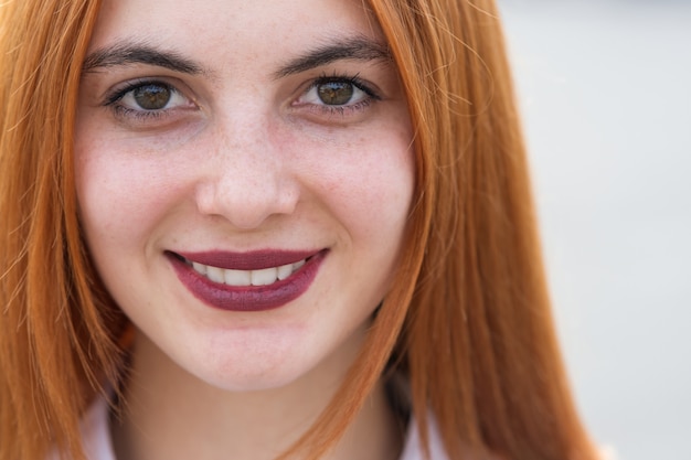 Closeup face portrait of a girl with red hair and clear eyes.