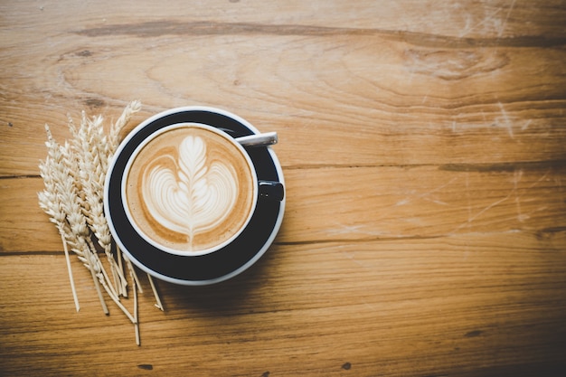 Closeup latte art de café tasse blanche sur la surface de la table en bois