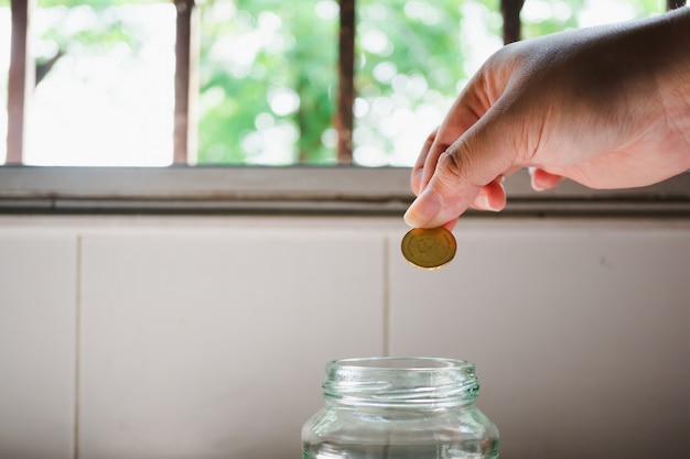 Closeup main mettre la pièce en bouteille en utilisant comme concept d&#39;économie et d&#39;affaires