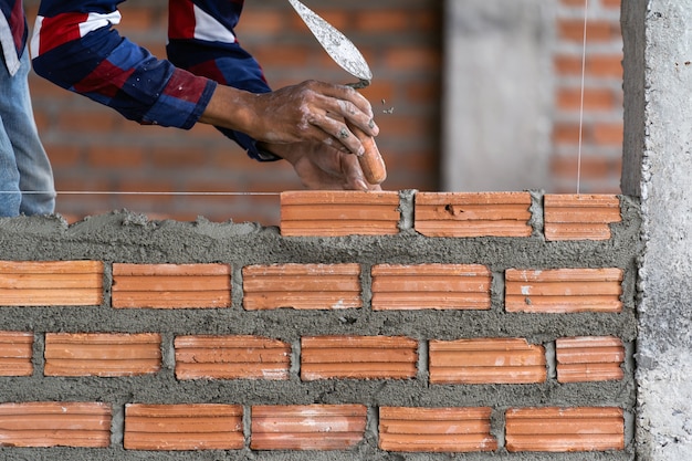 Closeup main travailleur de la construction professionnelle pose de briques dans le nouveau site industriel