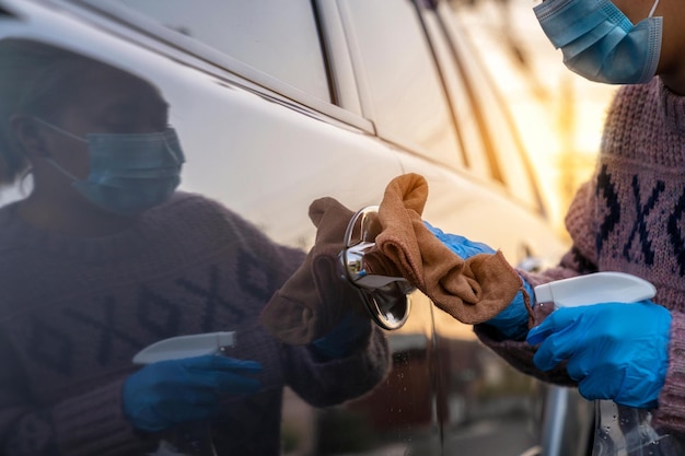 Closeup mains pulvérisant à partir d'une bouteille pour désinfecter la porte de la voiture Antiseptique désinfectant propreté et soins de santéAnti-bactérien et coronavirus COVID19