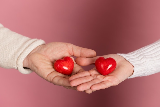 Closeup mains tenant coeur sur fond rose concept de la saint-valentin