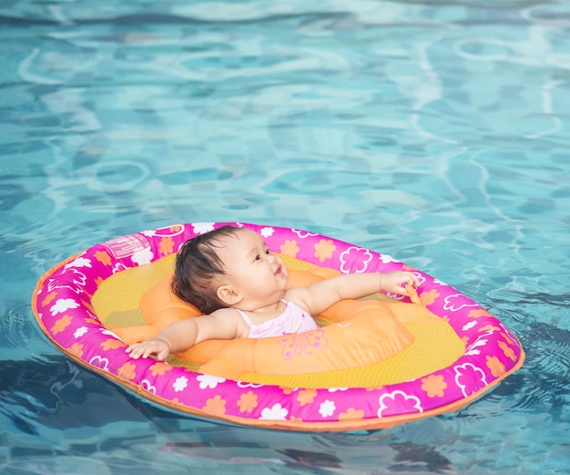 Closeup petite fille s&#39;asseoir dans un bateau pour les enfants dans le fond de la piscine avec espace de copie