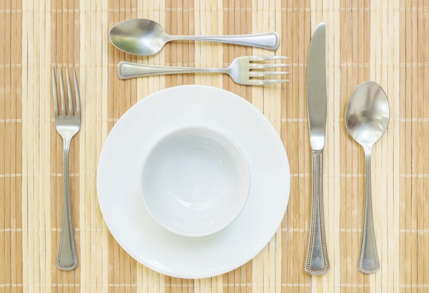 Closeup plat en céramique avec une fourchette en acier inoxydable et une cuillère et un couteau sur la table à manger