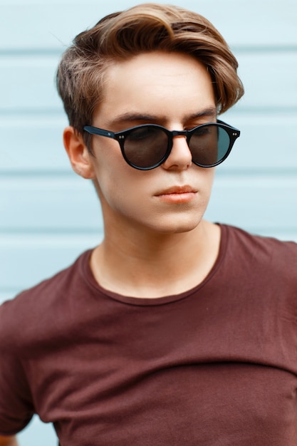 Closeup portrait d'un bel homme avec la coiffure en lunettes de soleil