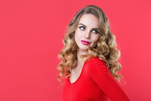 Closeup portrait d'une belle femme aux cheveux bouclés sur fond rouge. Beauté et mode.