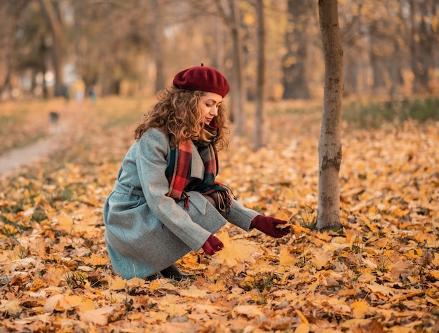 Closeup portrait de belle fille souriante tenant des feuilles d'automne dans le parc.