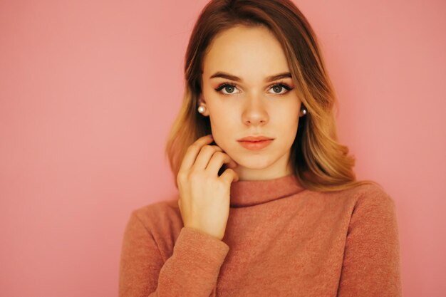 Closeup portrait belle jeune femme debout sur un fond rose et posant pour la caméra