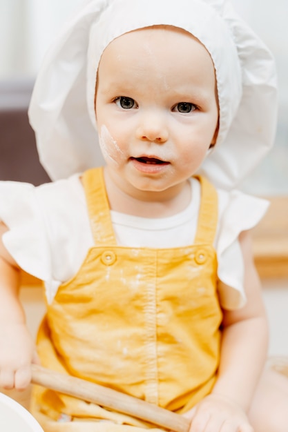 Closeup portrait d'une charmante petite fille crasseuse caucasienne curieuse dans un costume de cuisinier