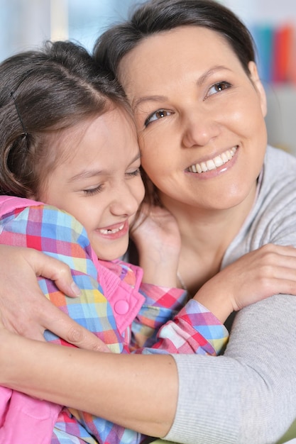 Closeup portrait d'une charmante petite fille étreignant avec maman à la maison