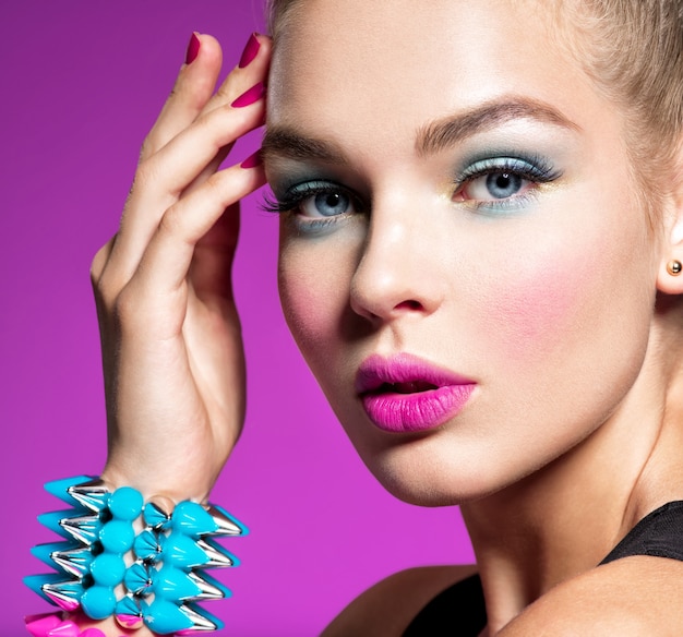 Closeup portrait d'une femme belle mode avec un maquillage lumineux Superbe fille glamour d'un mur rose jolie fille élégante. Portrait d'une jeune fille avec des épines de bracelets