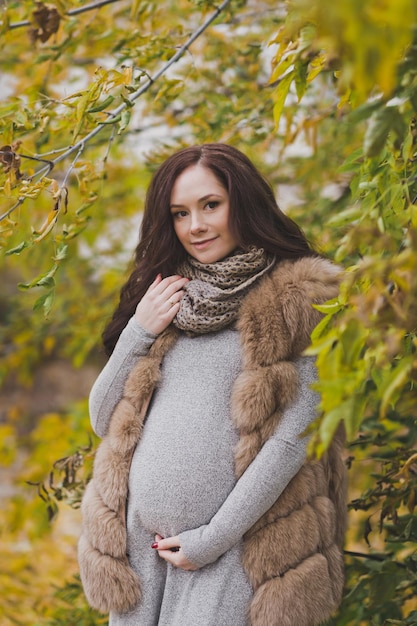 Closeup portrait d'une fille enceinte parmi les feuilles jaunissantes du tre