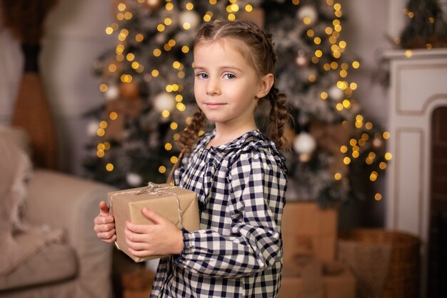 Closeup portrait heureuse petite fille avec cadeau de Noël à la maison