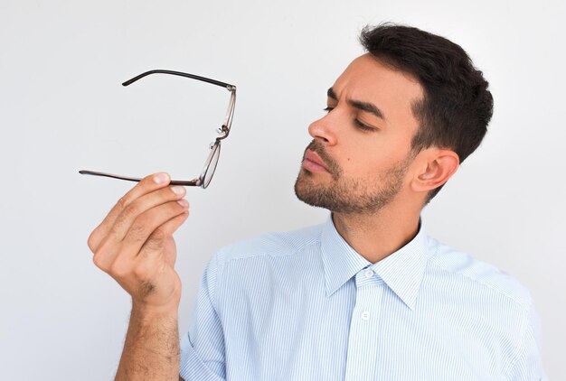 Closeup portrait horizontal de beau mâle sérieux mal rasé touche le bord des lunettes décident de porter posant sur fond de studio blanc Caucasien jeune homme confiant choisir des lunettes Gens