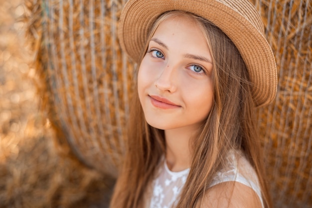 Closeup portrait d'une jeune fille dans une robe blanche légère et un chapeau