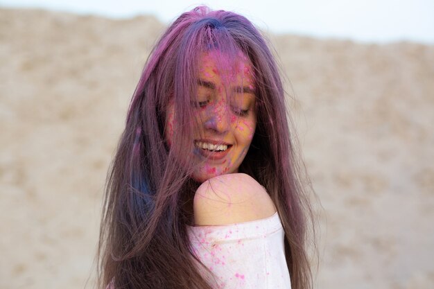 Closeup portrait de joyeux modèle brune célébrant le festival des couleurs Holi dans le désert. Espace pour le texte