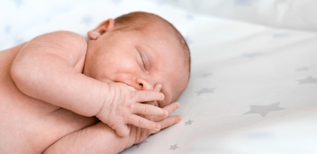 Closeup portrait de nouveau-né dormant sur une couverture blanche. Mise au point douce. Un bébé d'une semaine dort sur le côté dans son lit. Enfant de 10 jours. Rêves d'enfance. Notion de santé.