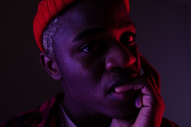 Closeup portrait of a black american man with big lips mordant son doigt dans la lumière au néon