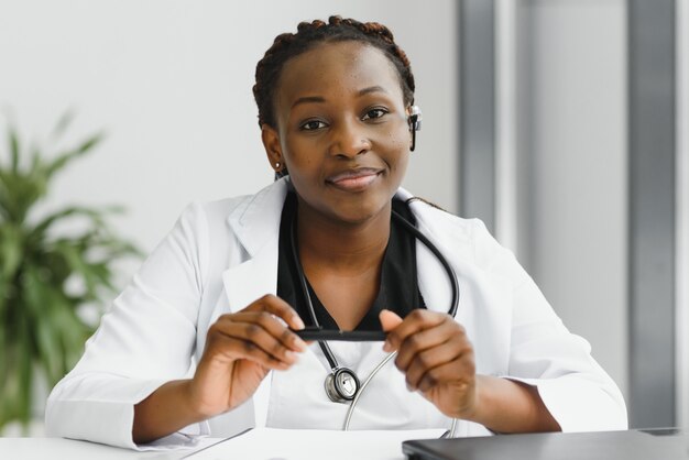 Photo closeup portrait of friendly, souriant professionnel de la santé féminin confiant avec blouse de laboratoire, stéthoscope, bras croisés