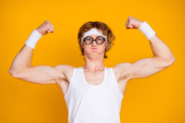 Closeup portrait of funky fier gingembre sportif gars montrant les biceps