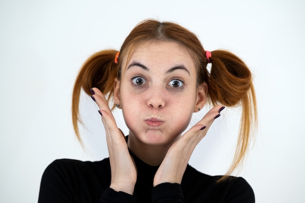 Closeup portrait of a funny redhead teenage girl with childish hairstyle