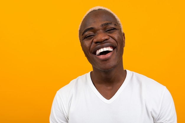 Closeup portrait of a smiling beautiful black blond African man on orange with copy space