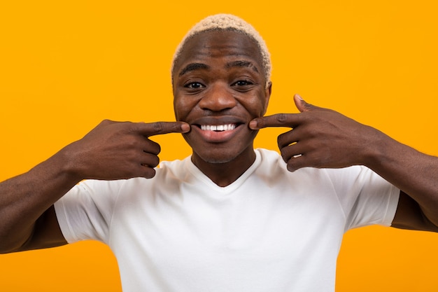 Closeup portrait of a smiling handsome black blond african man with grimace on orange