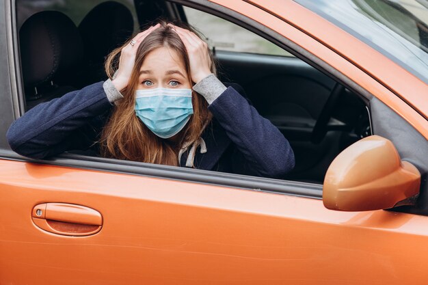 Closeup portrait of a woman in a medical mask in a car. épidémie de coronavirus. SRAS-CoV-2. Arrêtez COVID-19.