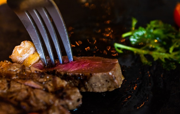 Closeup steak coupé en tranches servi sur assiette avec une cuillère pleine d&#39;épices.