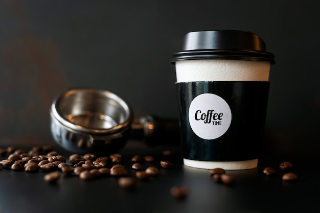 Closeup tasse de papier et grain de café sur tableau noir