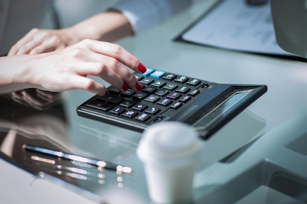 Closeupbusiness femme à l'aide d'une calculatrice sur le lieu de travail