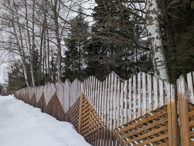 clôture en bois blanche et brune dans une forêt enneigée