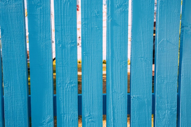 Clôture en bois décorative peinte en bleu dans la cour de la maison avec une pelouse verte luxuriante