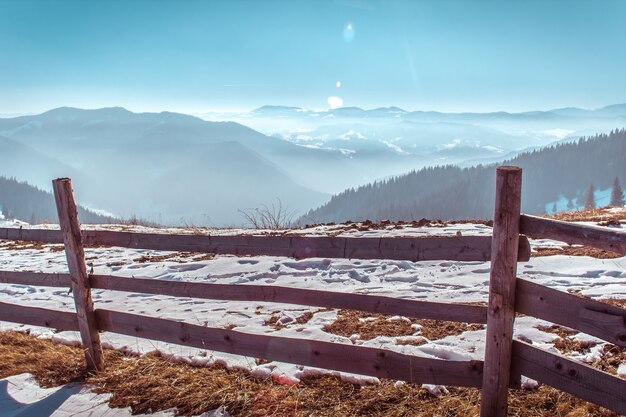 Clôture en bois sur le fond des montagnes d&#39;hiver dans la neige