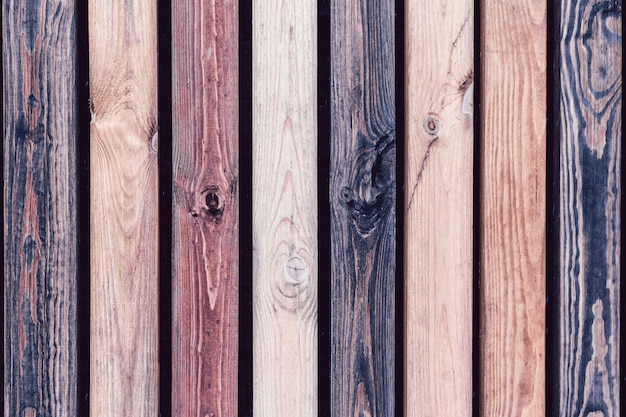 Clôture en bois rustique faite de planches traitées de couleurs différentes. Mur de fond vertical en bois de pin vintage dans un style vintage.