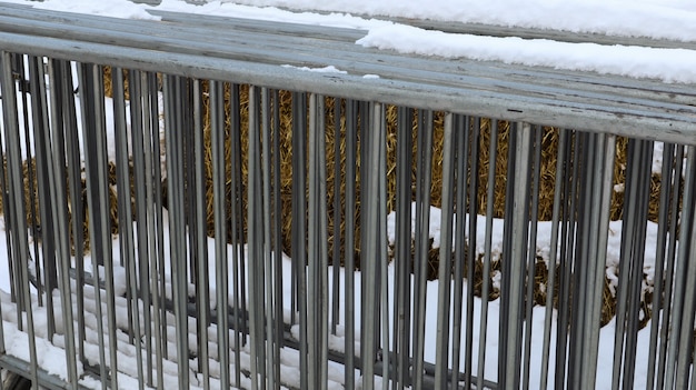 Une clôture d'événement en métal portable est conservée au même endroit à la foire dans la neige à l'extérieur en hiver. Grilles grises pour encombrer la zone et organiser la file d'attente pour l'événement.